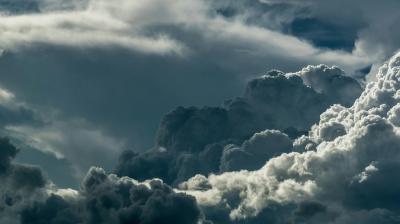Dark, dense clouds fill the sky with patches of sunlight highlighting their edges, suggesting an approaching storm or unsettled weather.