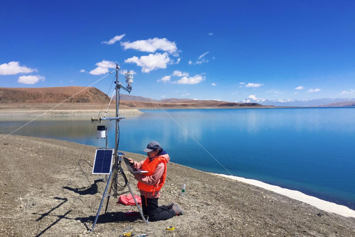 A man is standing next to a lake with a device in front of him.