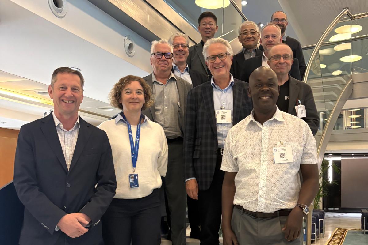 A group of twelve professionally dressed adults stands and smiles for a photo on a staircase in a modern indoor setting.