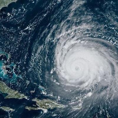 Satellite image showing a large hurricane with a well-defined eye over the Atlantic Ocean, approaching the southeastern coast of the United States and the Caribbean.