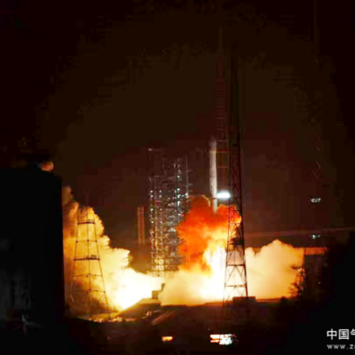 A rocket launches at night, emitting bright flames and smoke, with metal structures and a lit-up tower visible in the background. Chinese text is present in the bottom right corner.