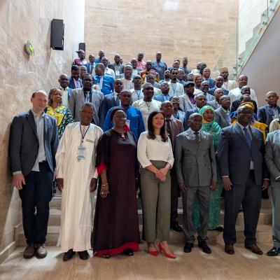 A large group of people in formal attire pose for a photo on a staircase inside a modern building.